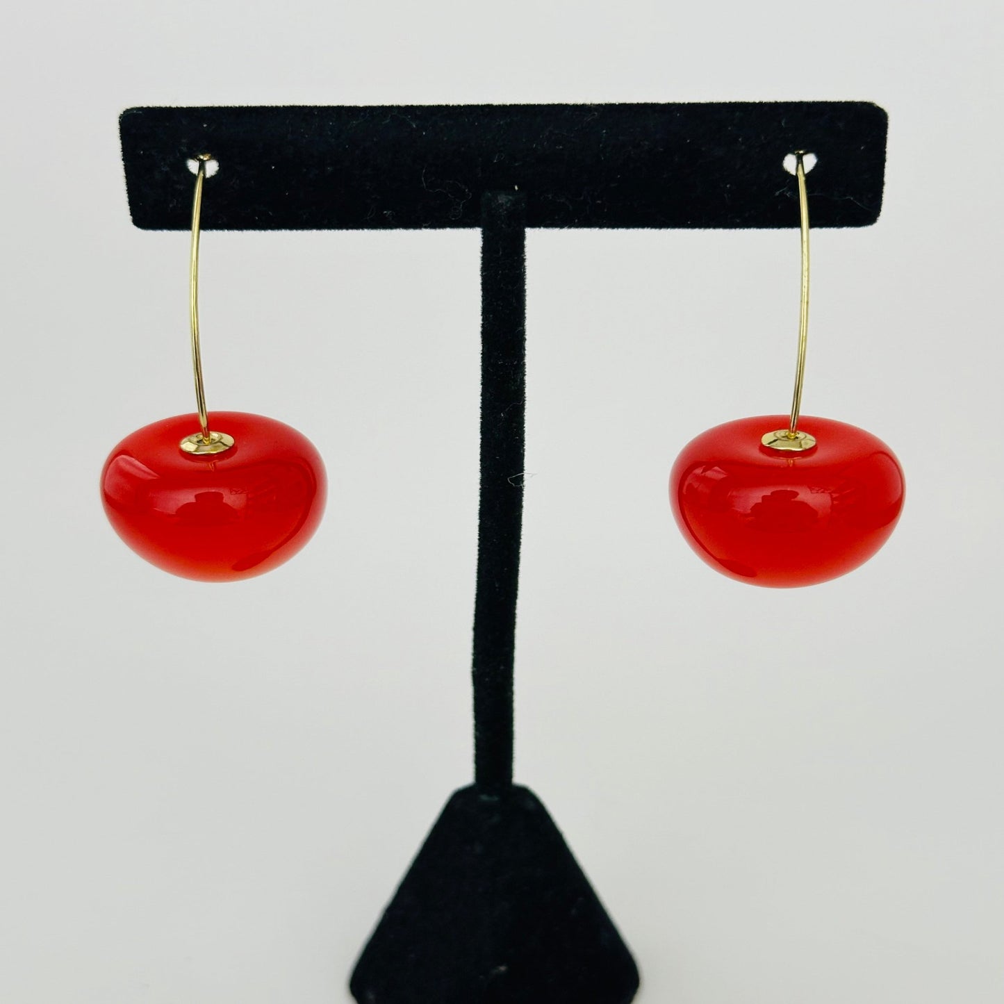 Close-up image of vibrant cherry earrings with red beads and green leaf details, ideal for playful and stylish looks."