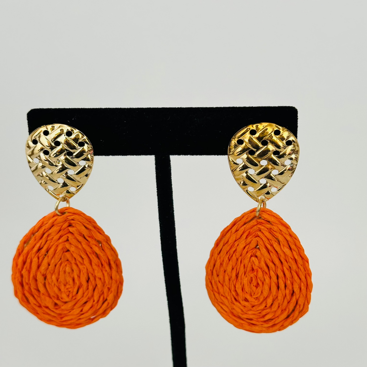 Close-up image of handmade raffia earrings with natural woven textures and vibrant colors, ideal for boho-chic outfits.

