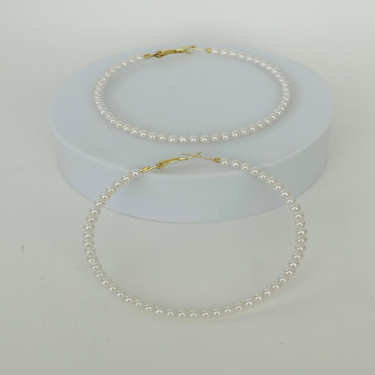 Close-up image of pearl hoop earrings featuring lustrous white pearls on a sleek gold hoop, ideal for elegant and modern styles.