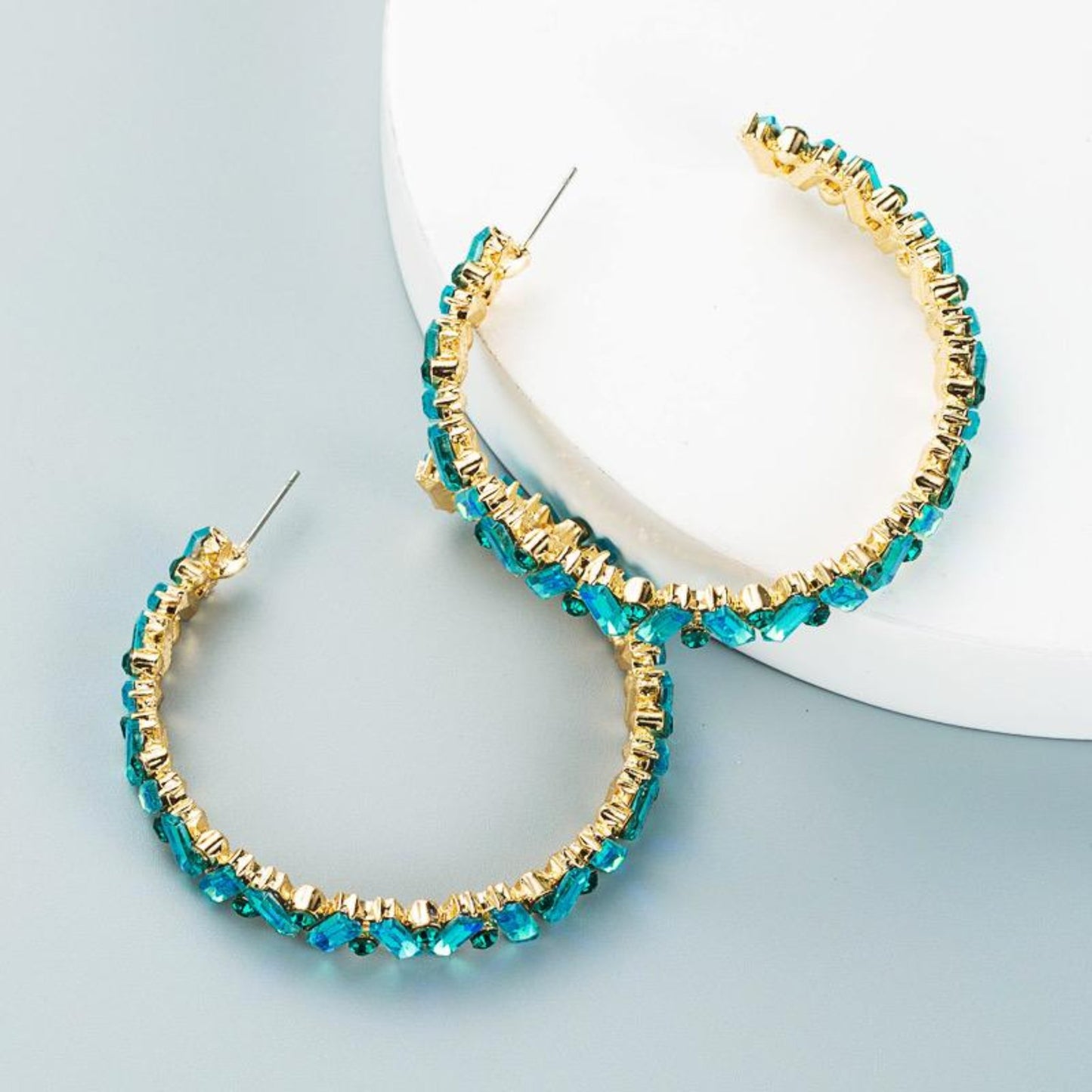 Blue rhinestone hoop earrings shimmering in light, featuring a sleek circular design for modern elegance."